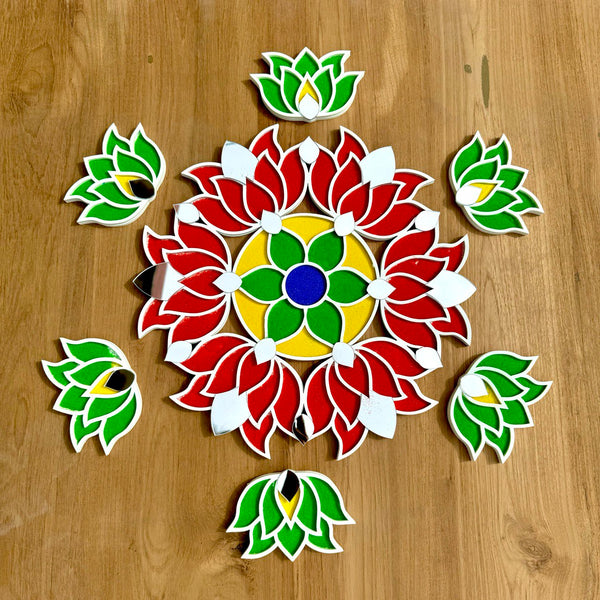 A colorful handcrafted rangoli design on a wooden surface, decorated with vibrant red, green, and yellow patterns, with additional small green and red shapes around it.