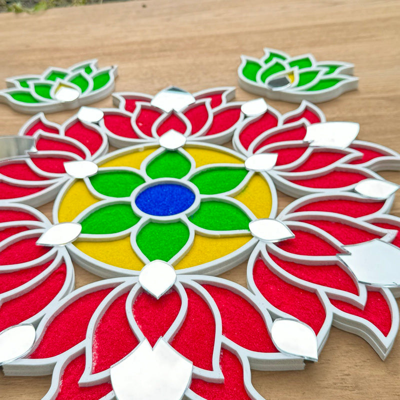 A colorful handcrafted rangoli design on a wooden surface, decorated with vibrant red, green, and yellow patterns, with additional small green and red shapes around it.